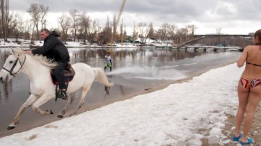 Hot Chick in a Bikini and Sandals Standing on a Frozen Riverside While a Guy on Horse Pulls Another Guy on a Wakeboard